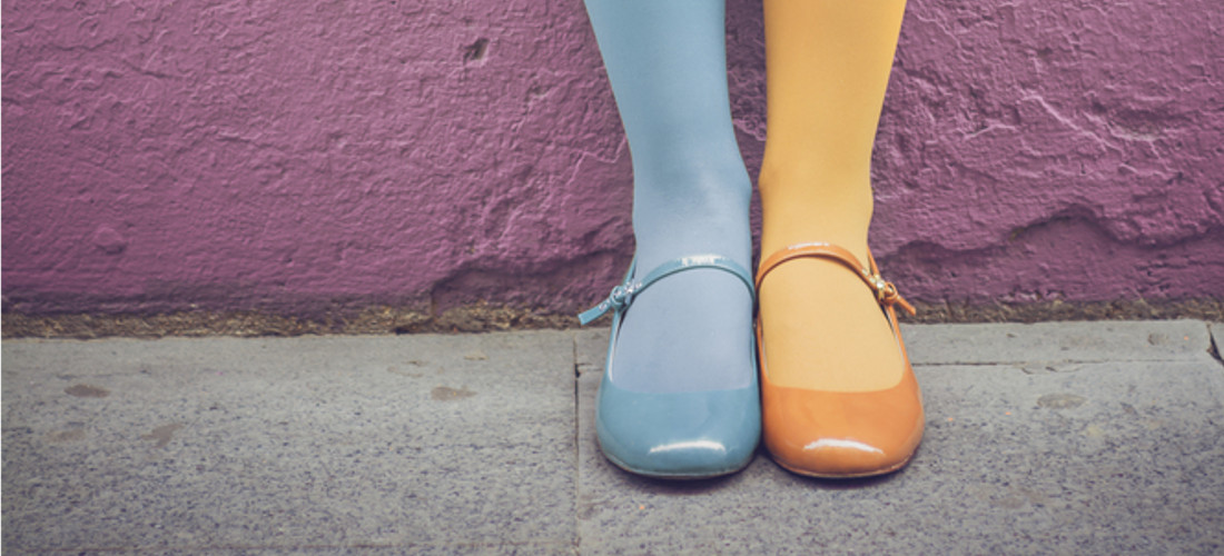 Das Foto zeigt zwei Füße mit jeweils unterschiedlicher Farben bei den Schuhen und der Strumpfhose.