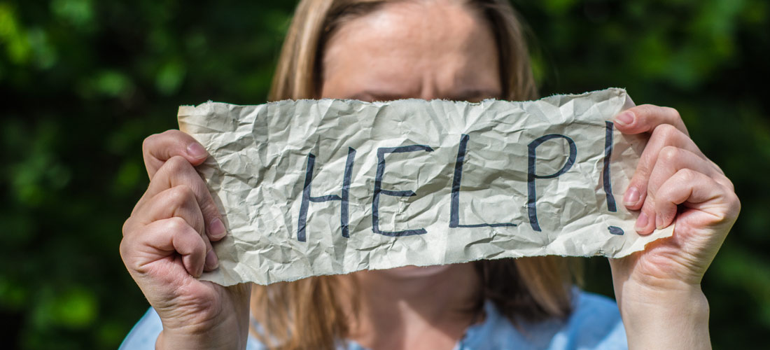 Mädchen hält einen Zettel mit der Aufschrift 'Help' vor ihr Gesicht