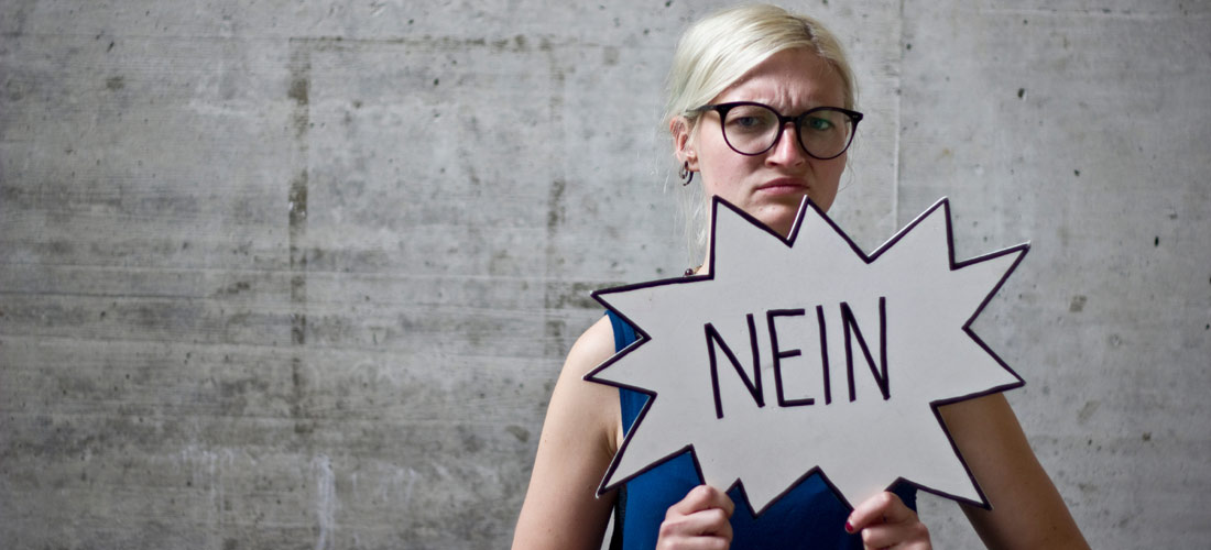 Das Foto zeigt ein Mädchen mit einer Brille, welches ein Schild in der Hand hält mit der Aufschift Nein